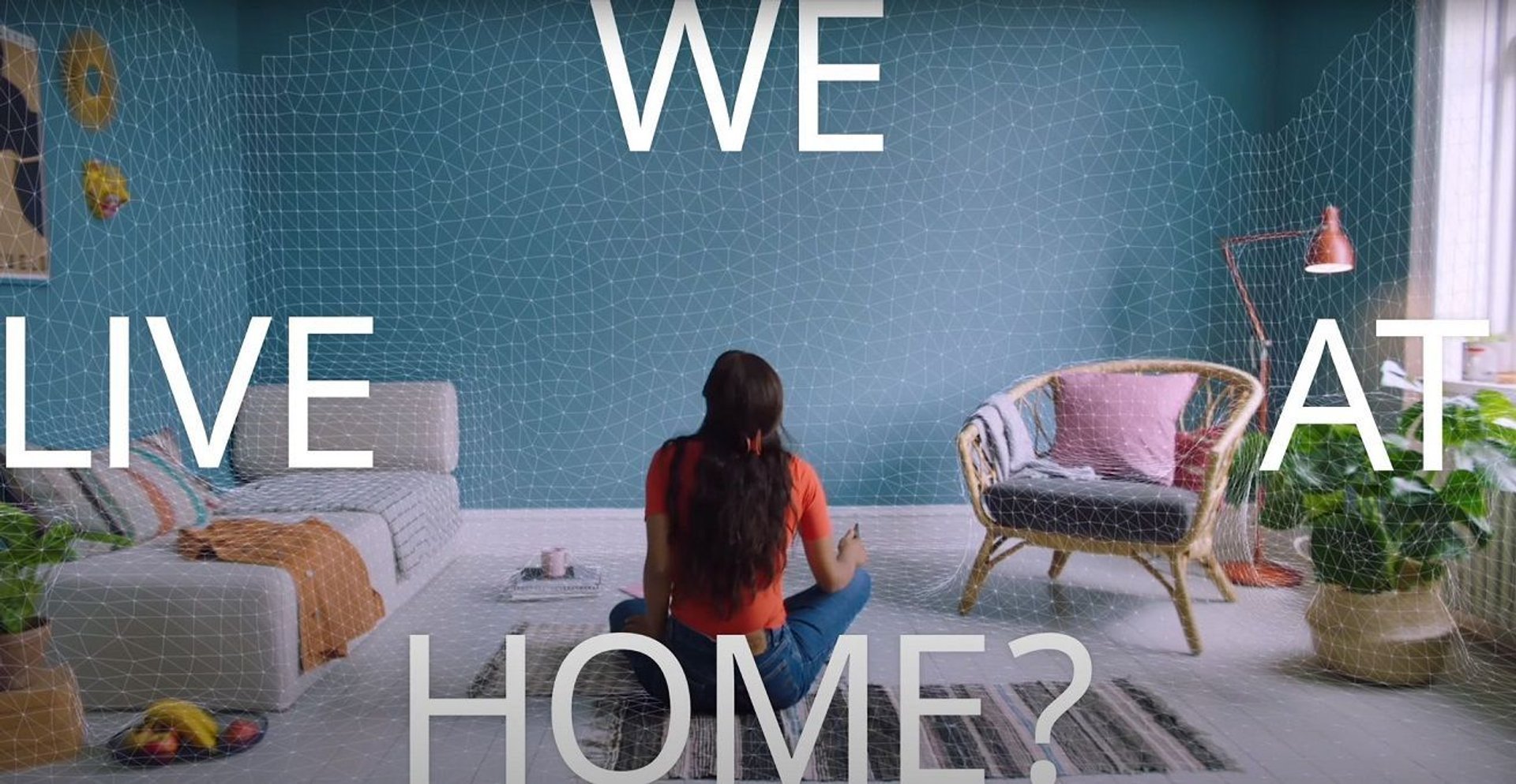 Fragment filmu wyprodukowanego przez Ikeę. Napis "WE LIVE AT HOME?" siatka na ścianach, kobieta na środku pokoju.