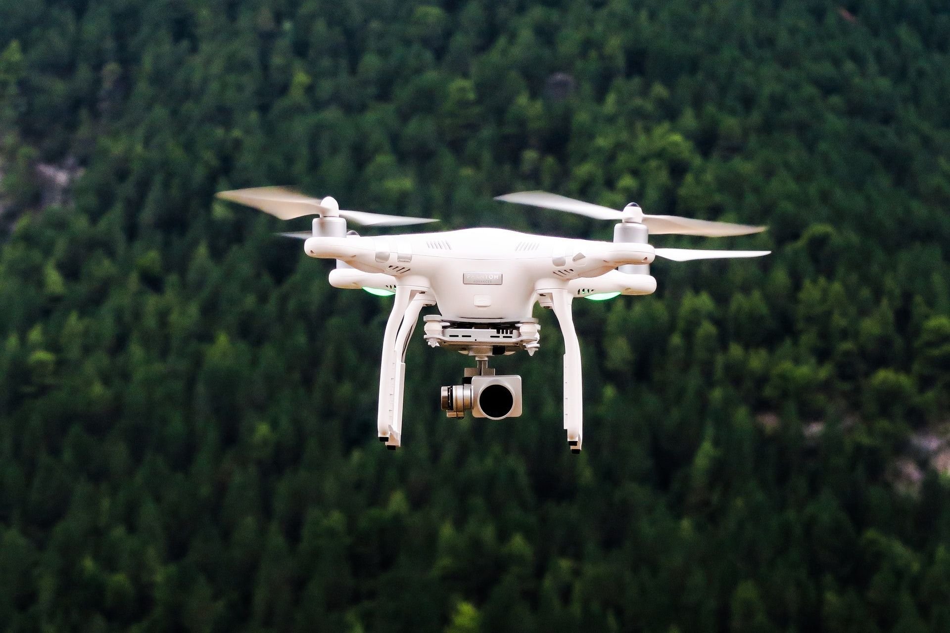 Biały dron frunący ponad lasem