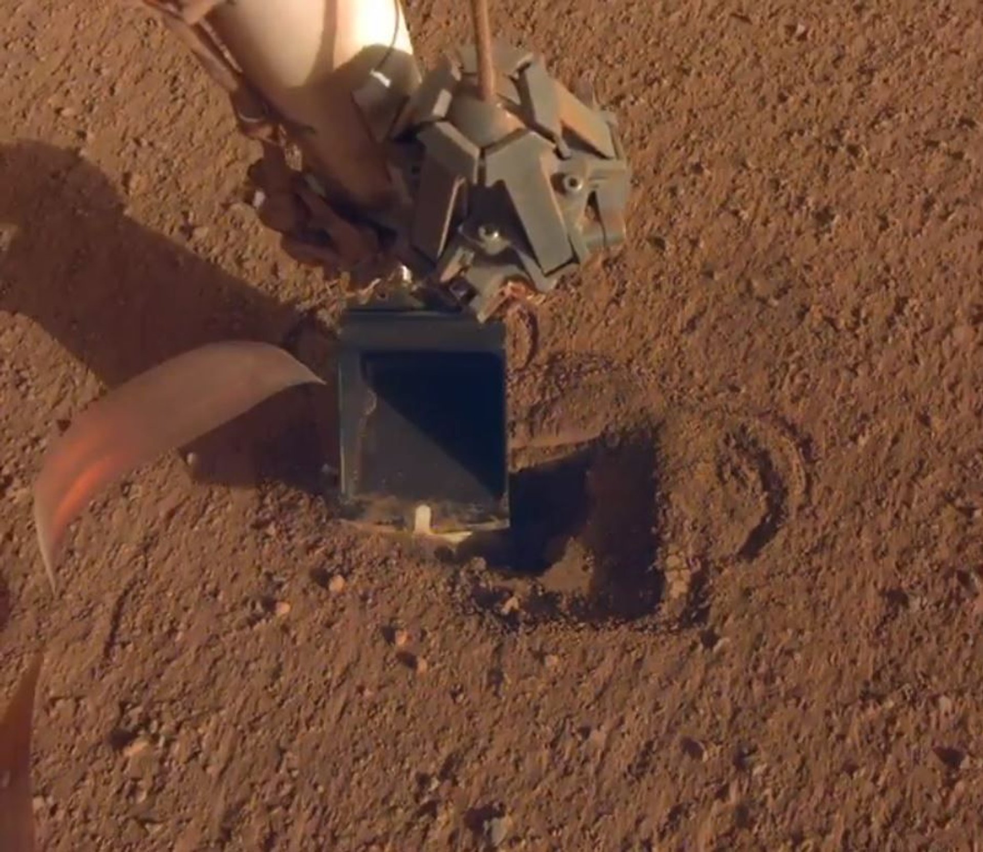 Ramie lądownika InSight wpychające sondę HP3 pod powierzchnię Marsa.
