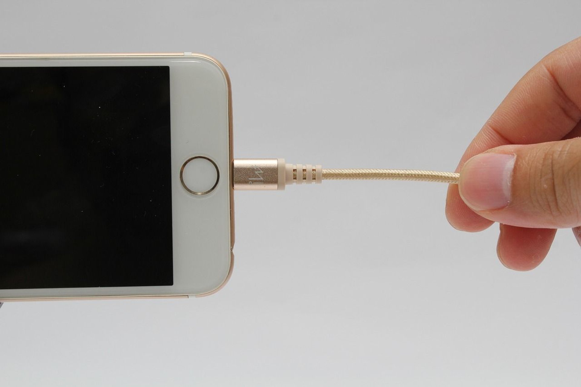 iPhone podłączony do kabla ładującego.