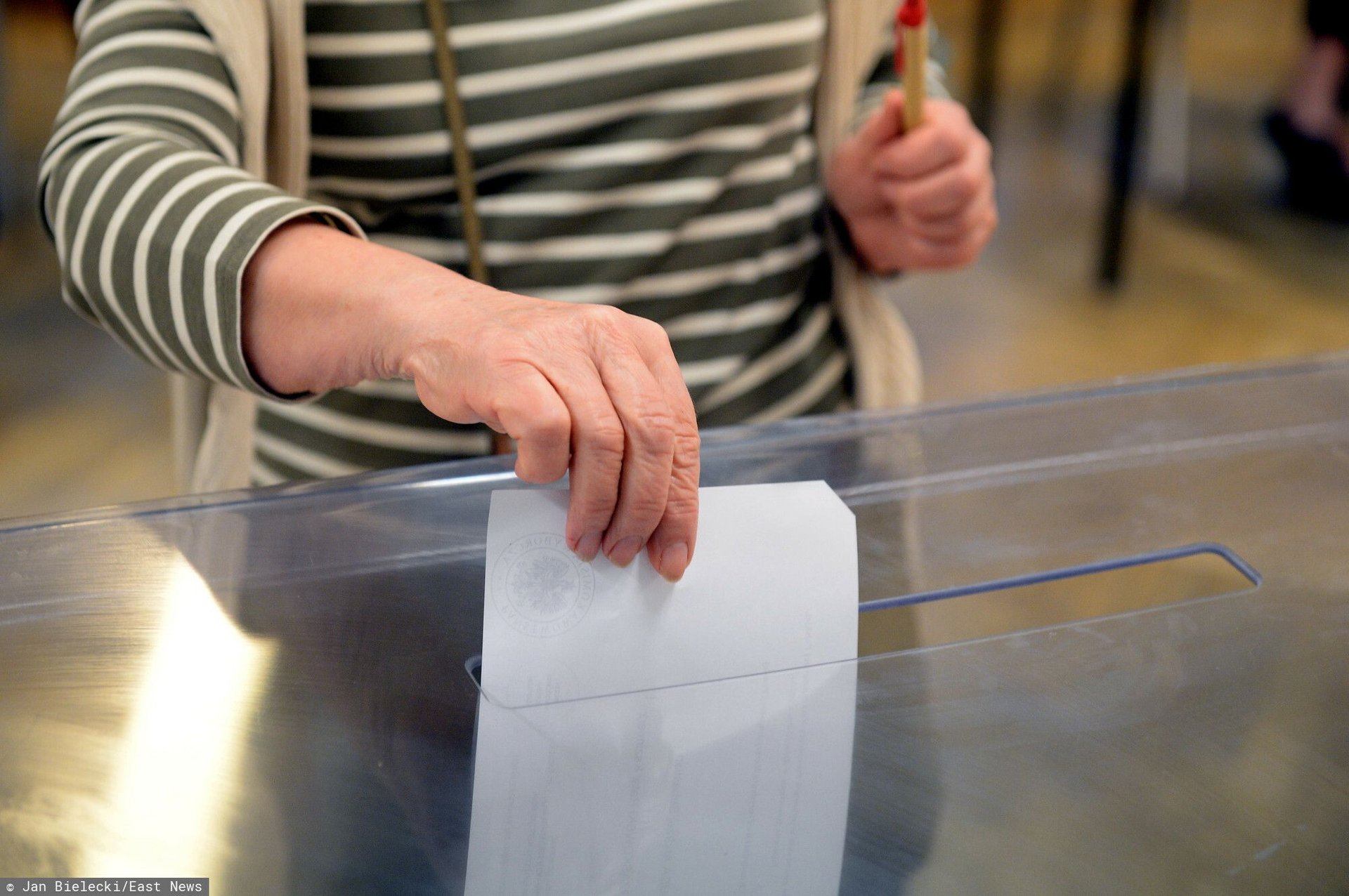 Kobieta wrzucająca kartę do głosowania do urny