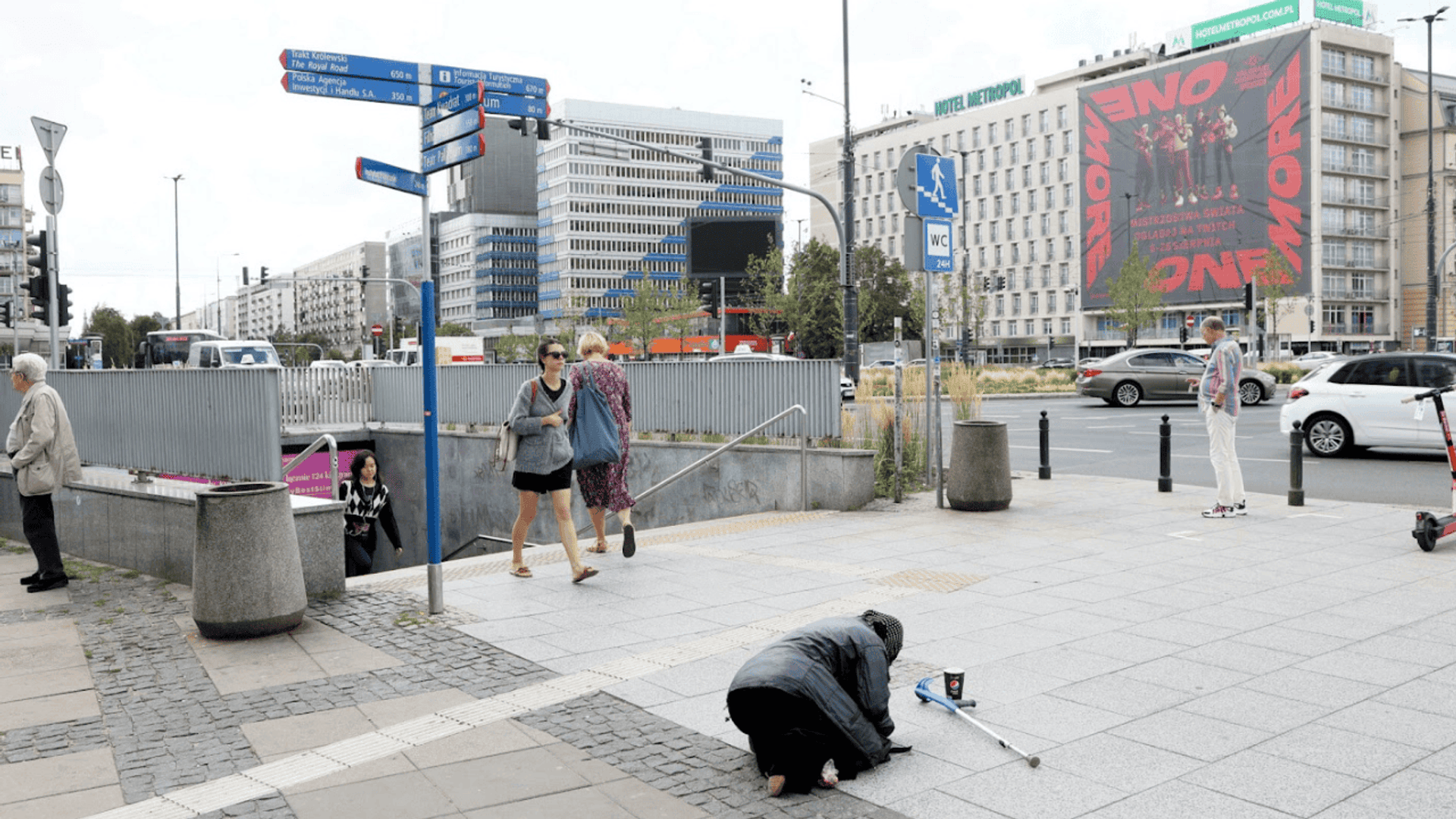 Osoba klęcząca na chodniku; ubóstwo