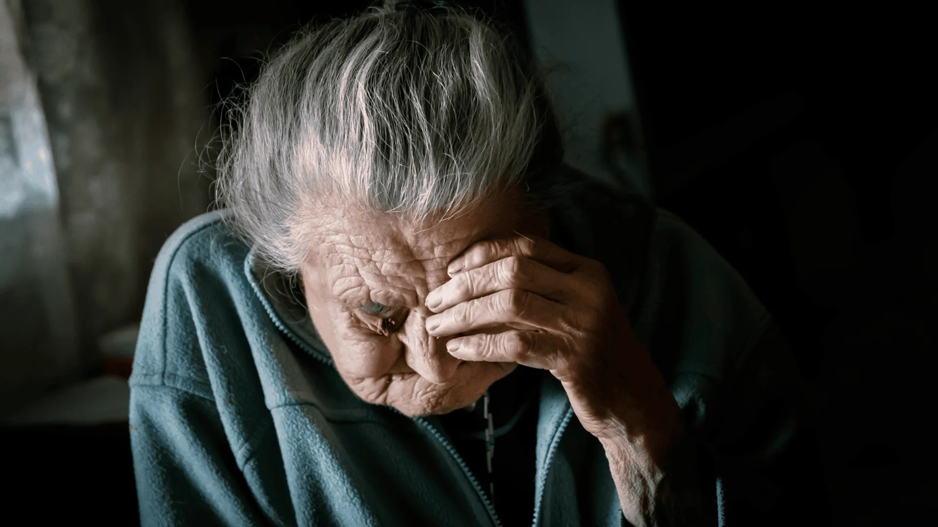 Starsza kobieta trzyma się za twarz