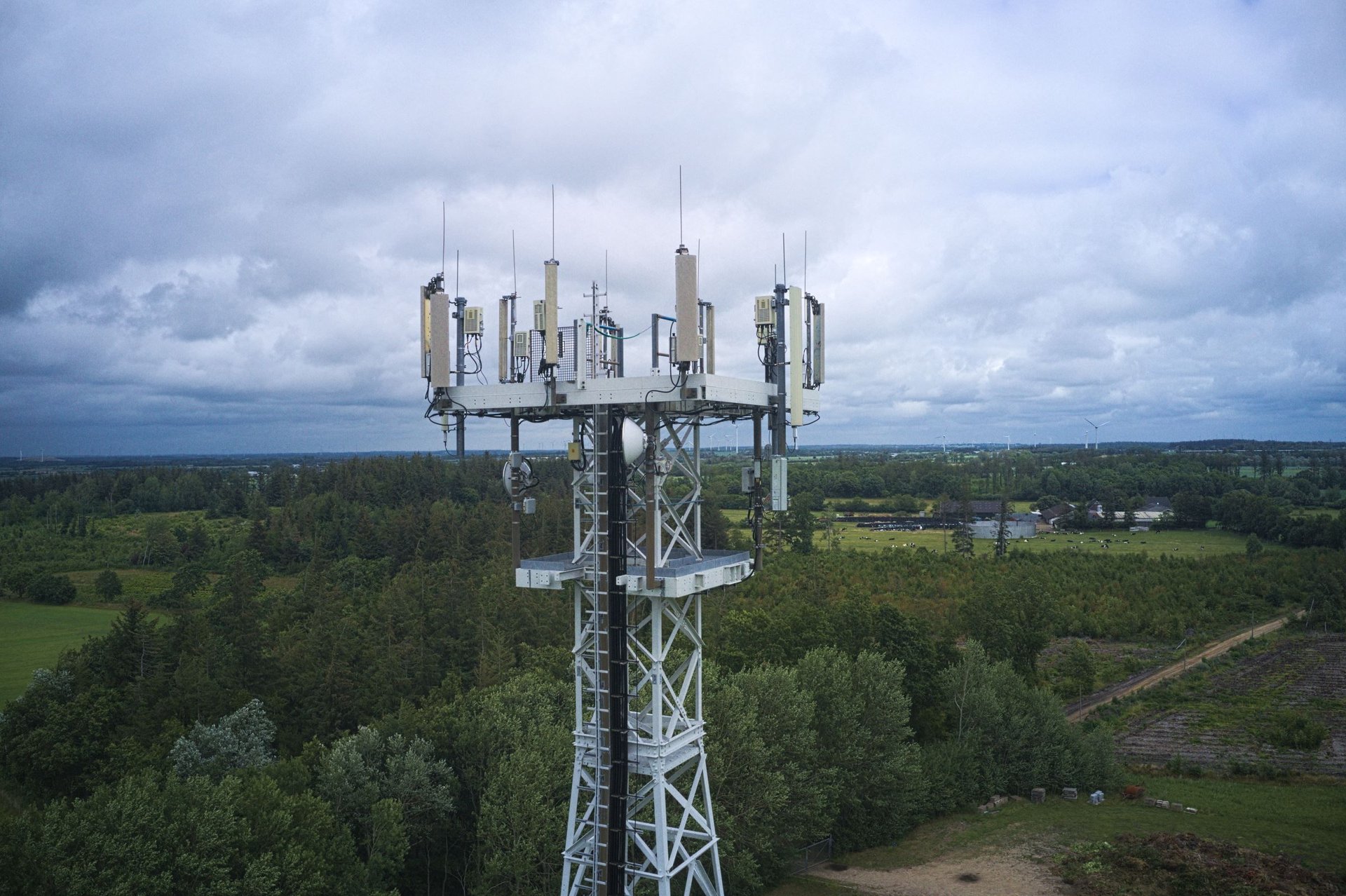 Antena radiowo-telewizyjna nadająca sygnał 5G. W tle horyzont, lasy, niebo.