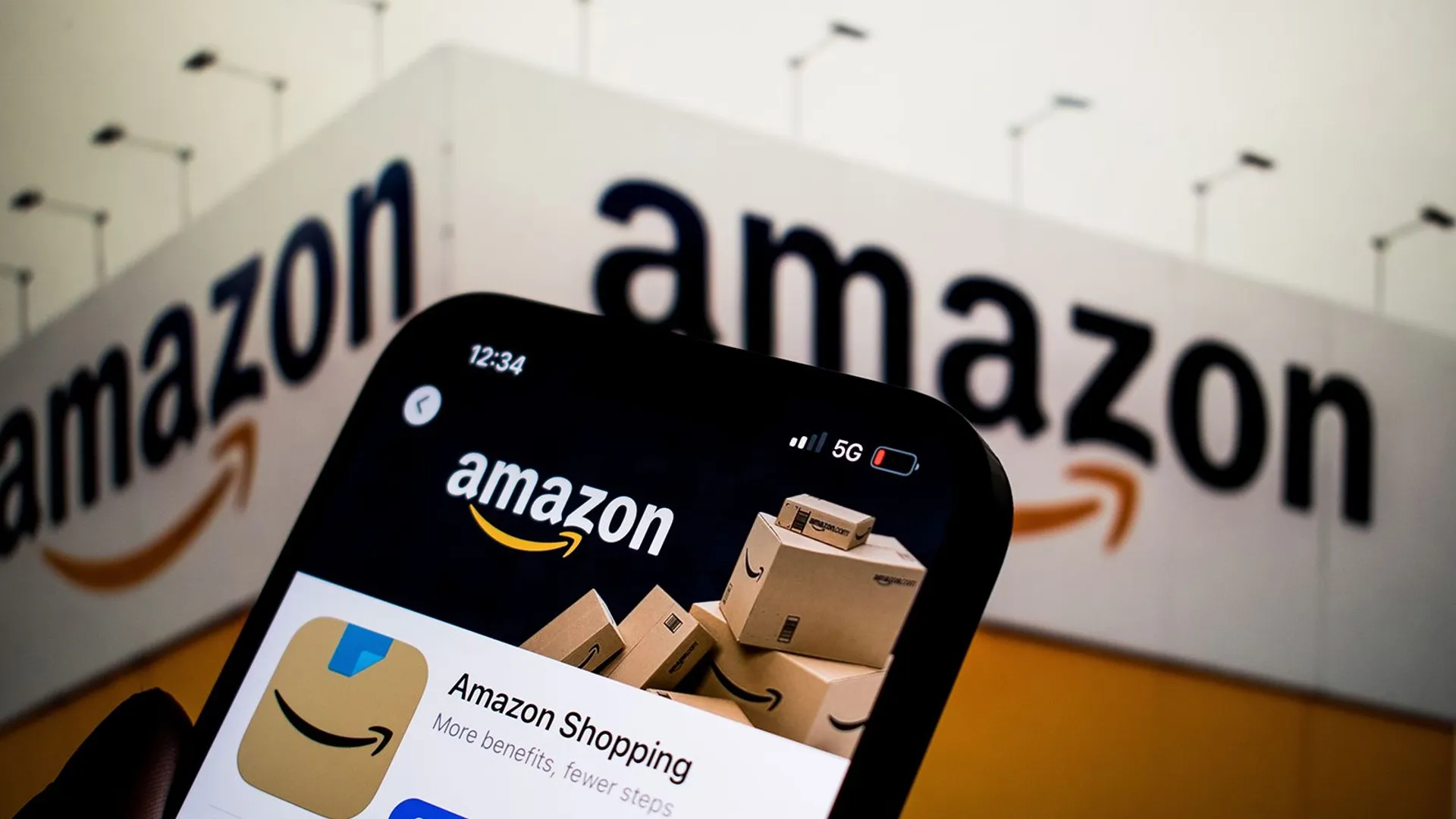 Mężczyzna trzyma smartfon z aplikacją Amazon wyświetloną na ekranie