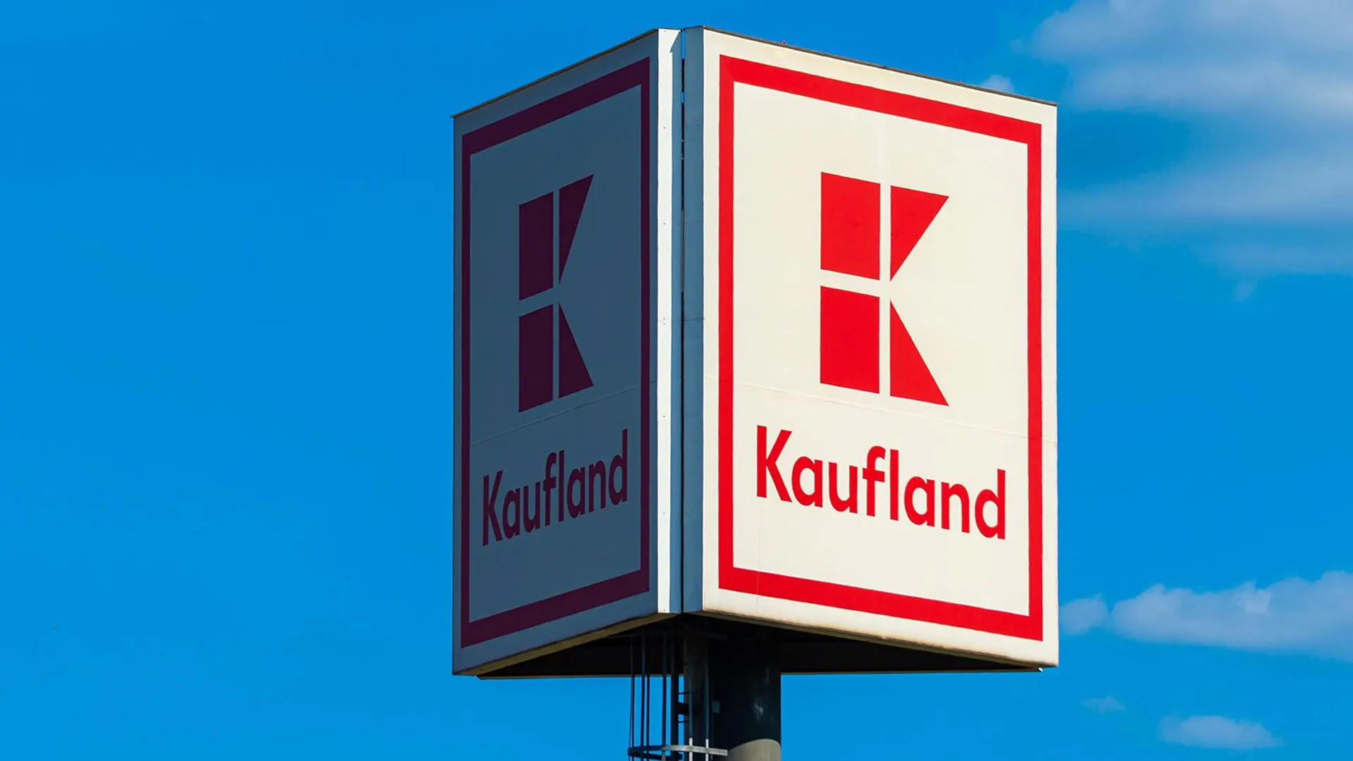 Logo sklepu Kaufland na niebieskim tle nieba. Kaufland to niemiecka sieć hipermarketów, należąca do Grupy Schwarz. Sieć supermarketów detalicznych, codzienne zakupy.