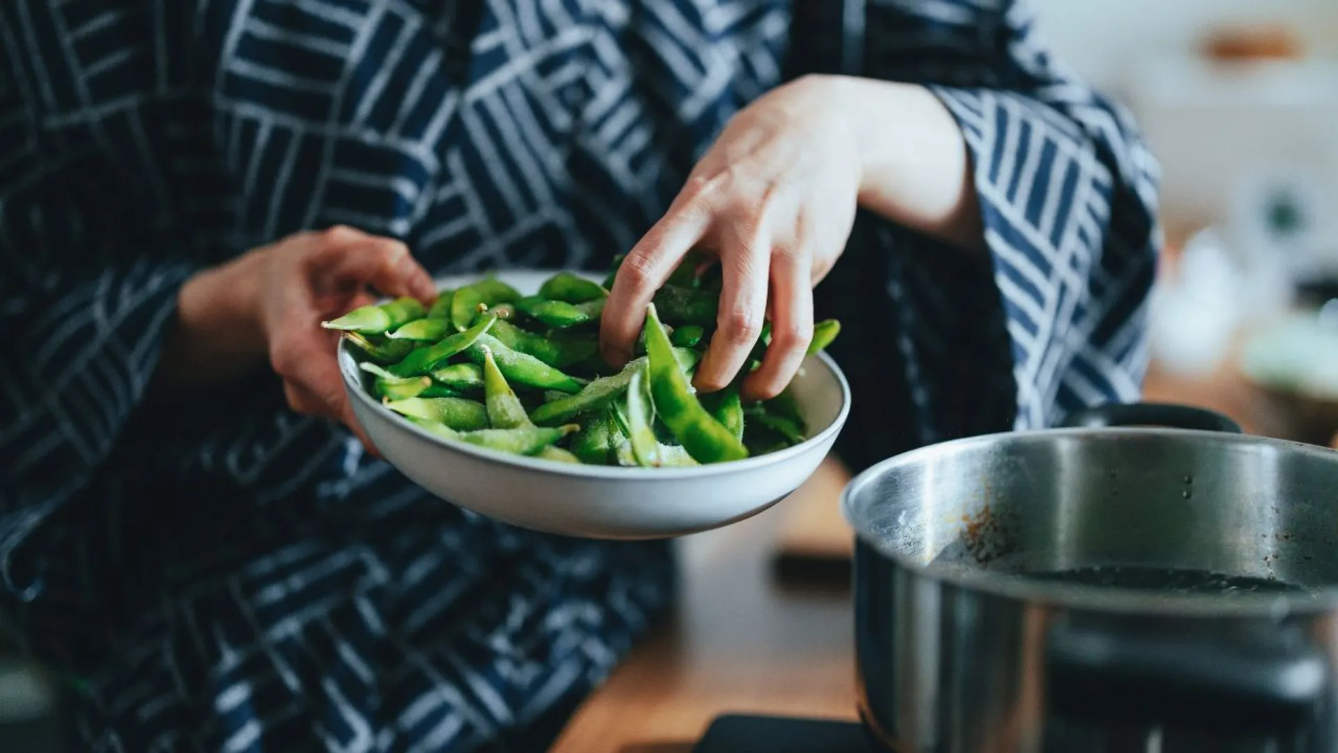 kobieta dodaje edamame do garnka