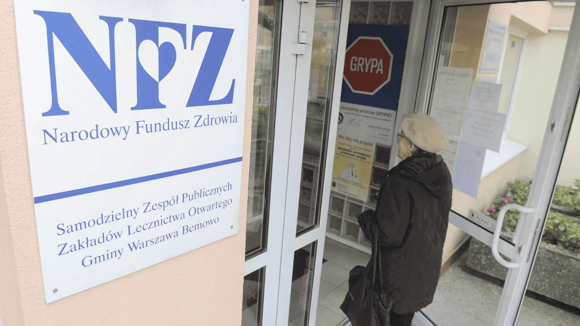 Pacjentka wchodzi do przychodni finansowanej przez Narodowy Fundusz Zdrowia.