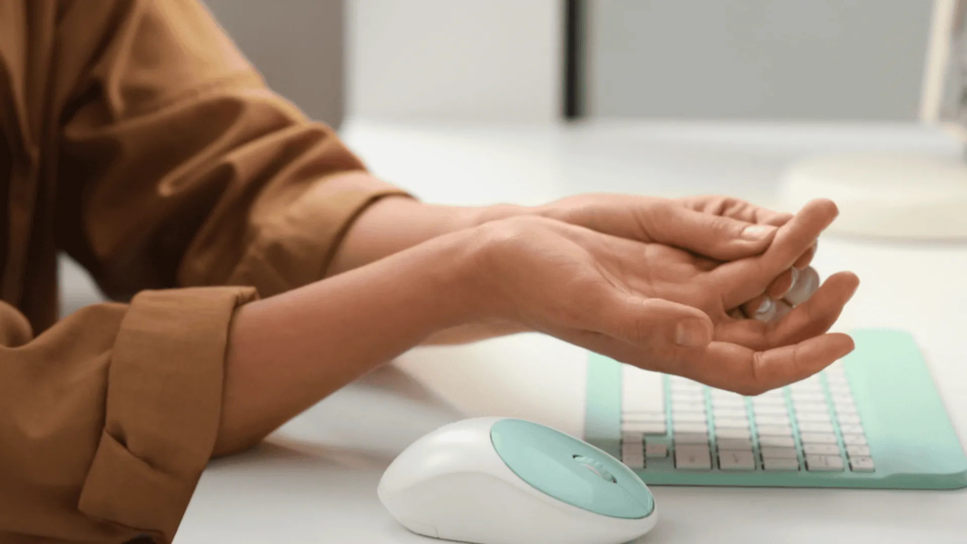 kobieta siedzi przy biurku, ogląda swoje palce