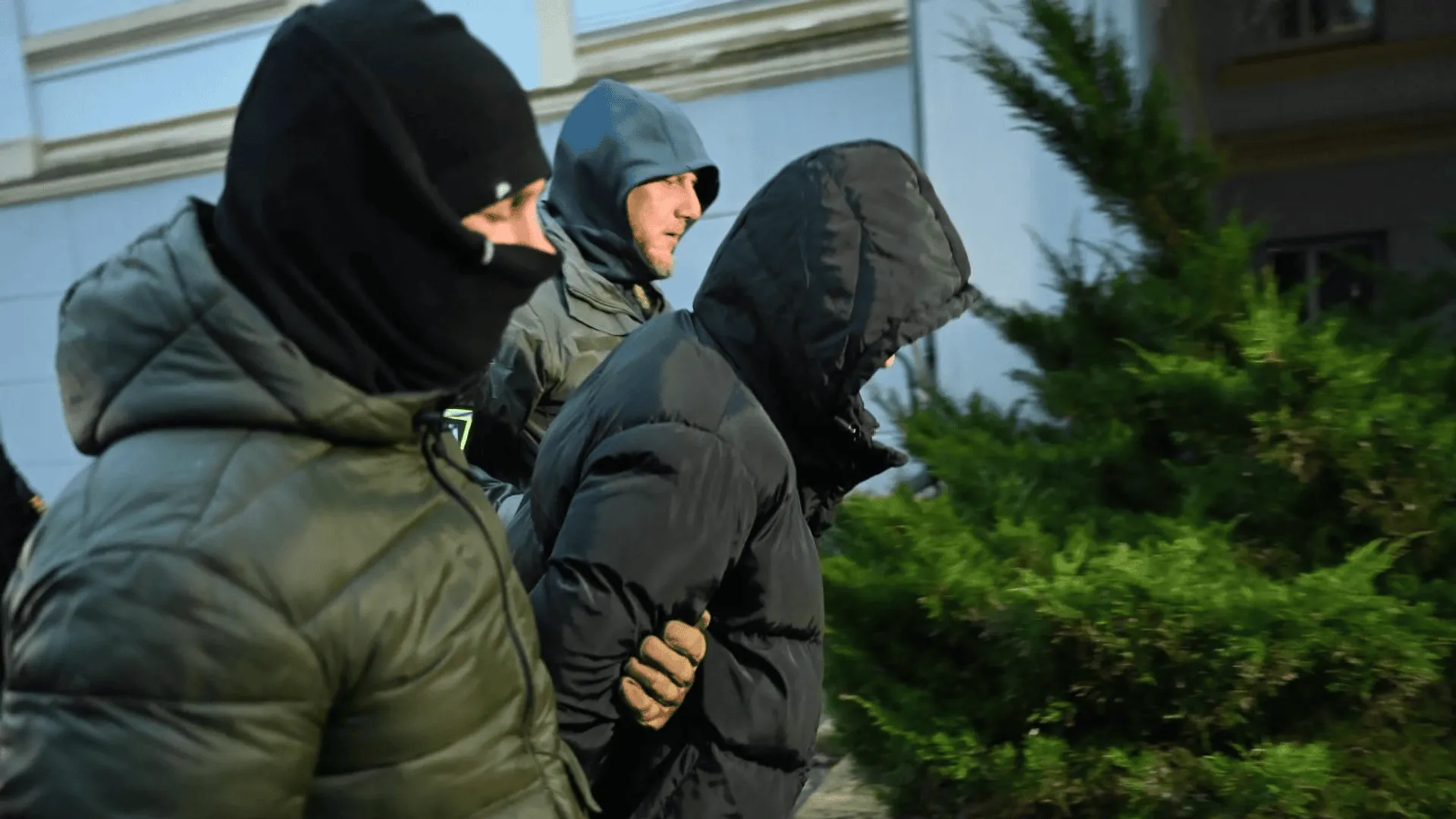 Funkcjonariusze policji prowadzą podejrzanego o popełnienie przestępstwa.