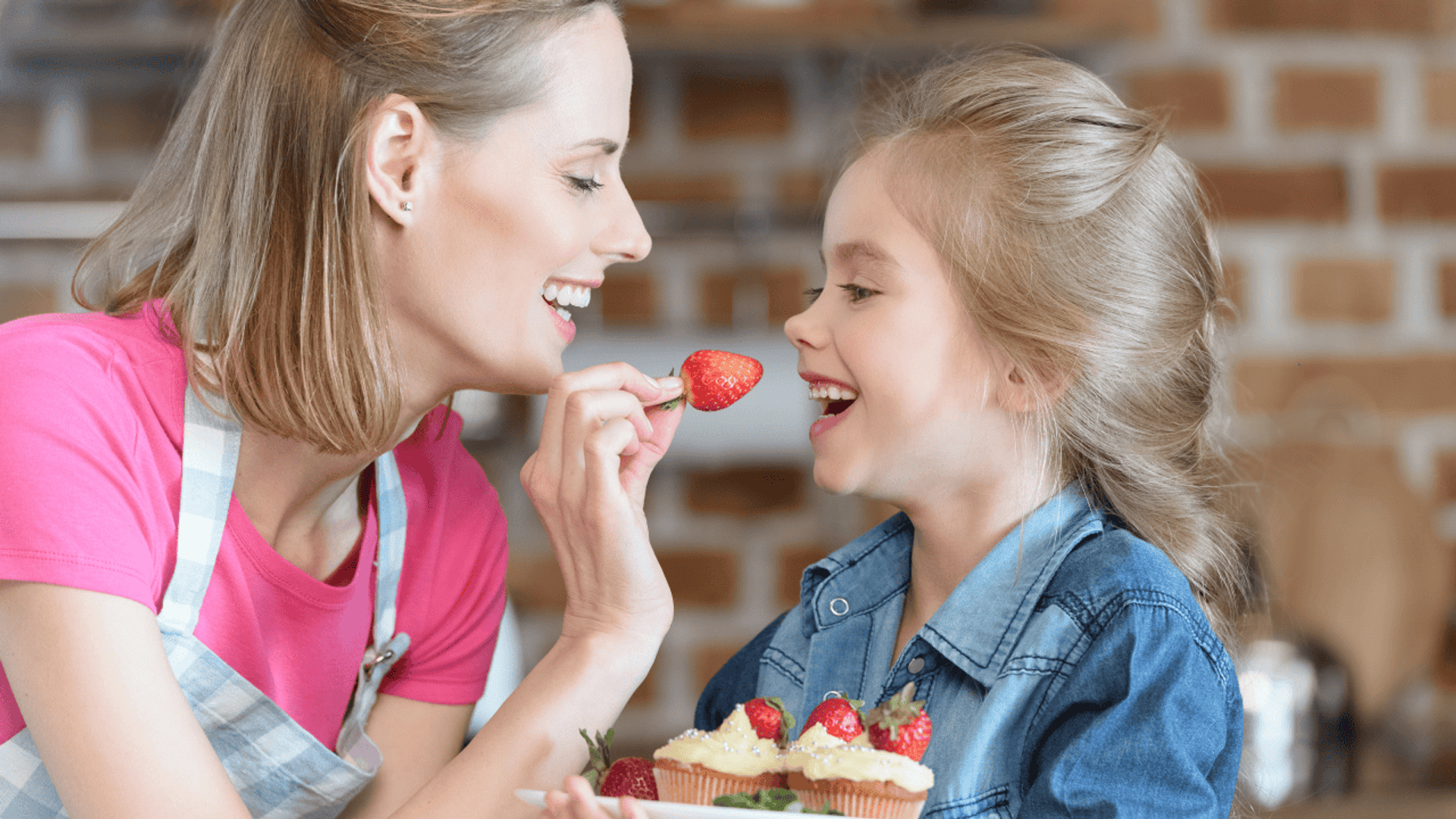 mama daje córce truskawkę