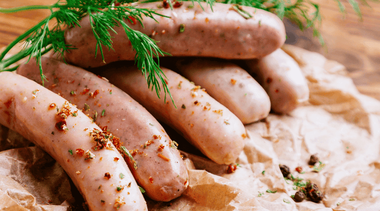 Biała kiełbasa pieczona w sosie chrzanowym. Intensywna w smaku i aromatyczna