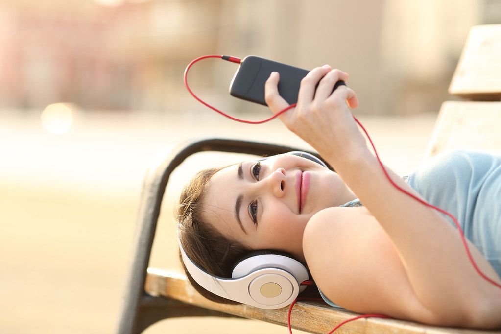 Dziewczyna w słuchawkach słuchająca muzyki z telefonu komórkowego.