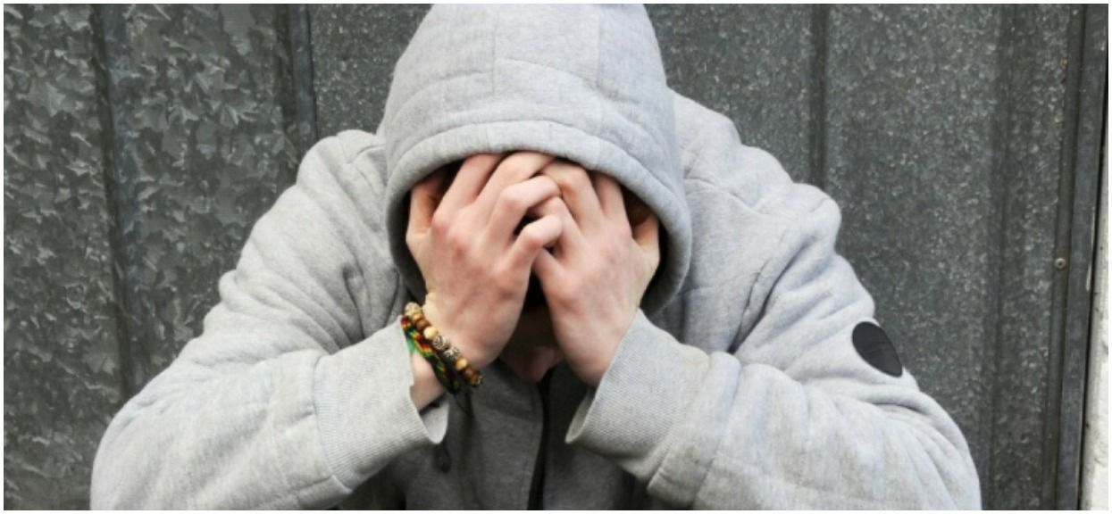 MODEL RELEASED. Depressed teenager. 18-year-old depressed teenage boy resting his head in his hands.
