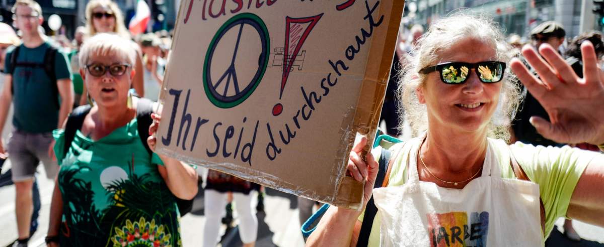 Two women hold a sign reading "Off the mask, you are sussed" as the take part in a demonstration by the initiative "Querdenken-711" with the slogan "the end of the pandemic-the day of freedom" to protest against the current measurements to curb the COVID-