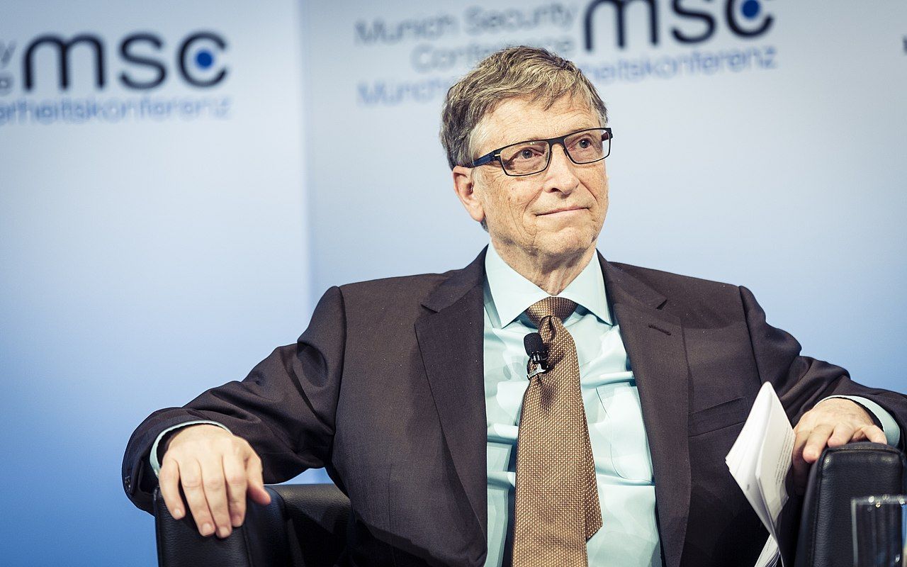 Bill Gates siedzi na krześle podczas konferencji.