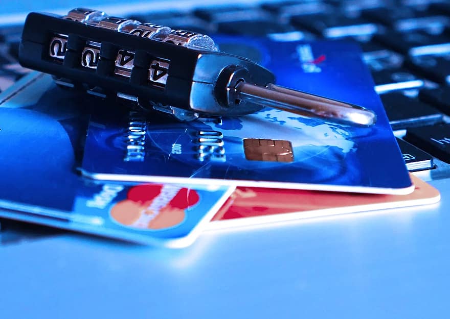 Karty kredytowe na klawiaturze laptopa i kłódka sugerująca zabezpieczenie.