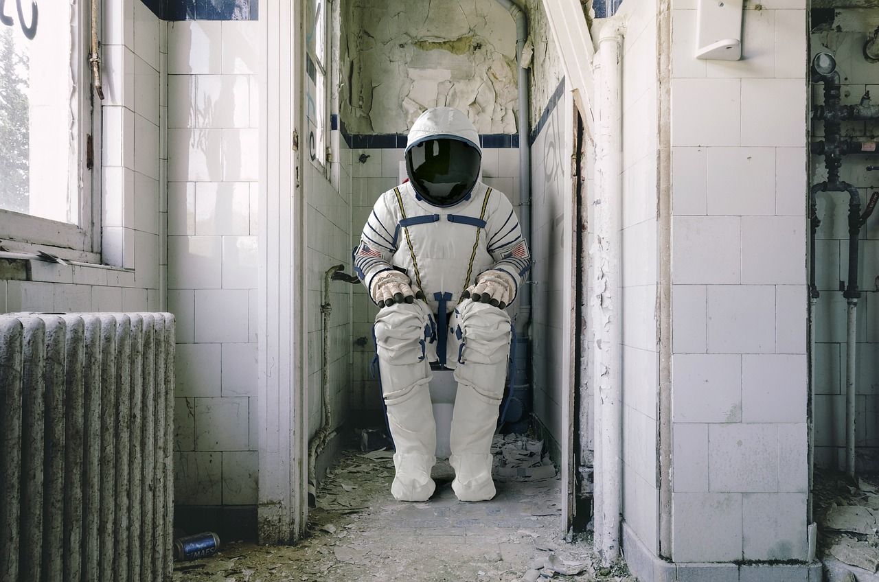 Astronauta w kombinezonie siedzi na toalecie w starej łazience.