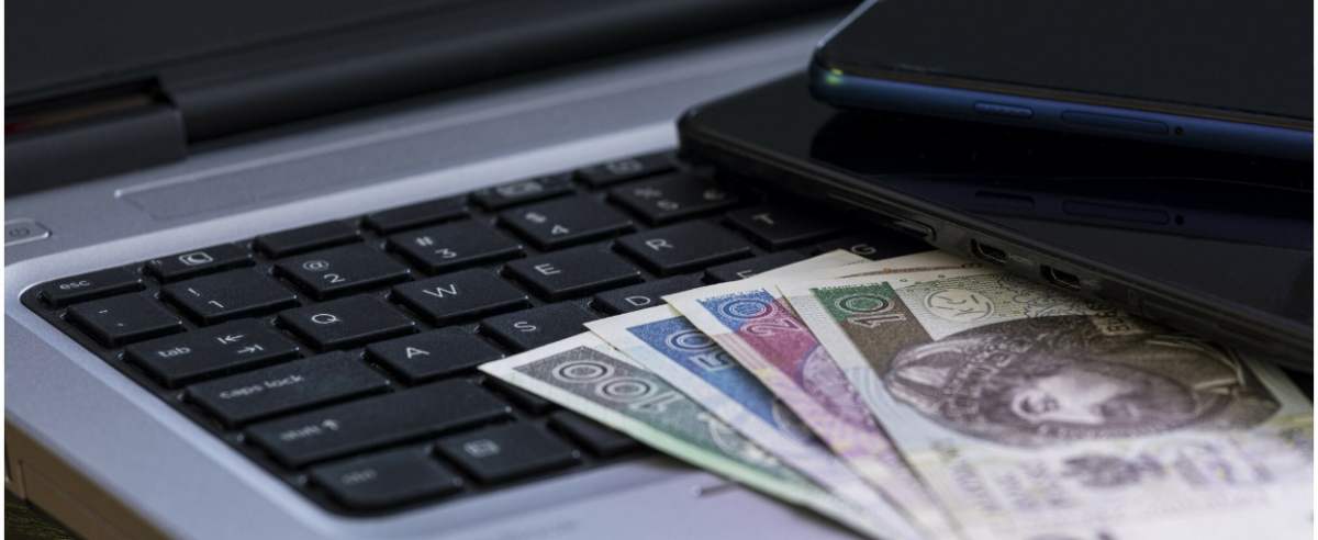 fot: Arkadiusz Ziolek/ East News. n/z Laptop, pieniadze, smartfon leza tablet na stole.