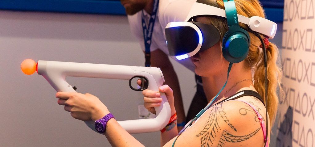 Kobieta korzystająca z headsetu PlayStation VR i specjalnego kontrolera.