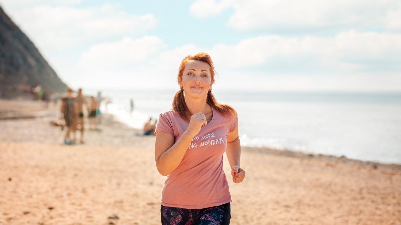Kobieta w średnim wieku biega po plaży