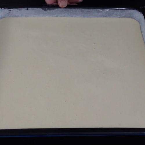 Ciasto na pizzę wyłożone na blachę
