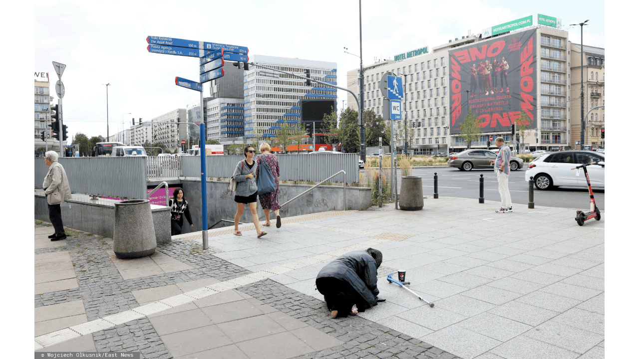 Osoba klęcząca na chodniku; ubóstwo