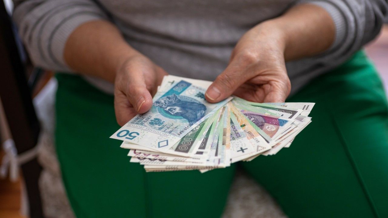Starsza kobieta trzyma w rękach pieniądze