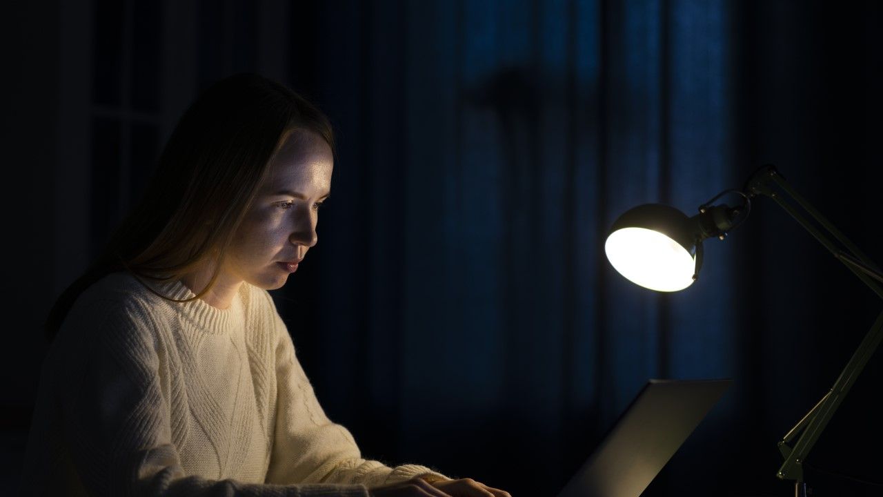 Młoda kobieta siedzi w nocy przy komputerze, lunatykuje