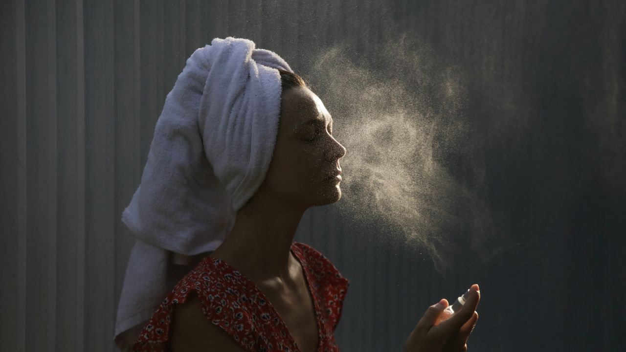 kobieta rozpylająca mgiełkę na twarzy