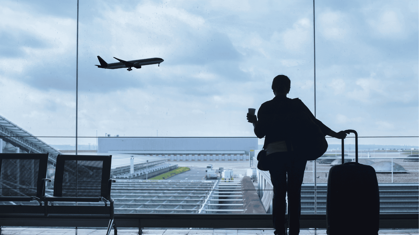 Kobieta na terminalu patrząca na odlatujący samolot.