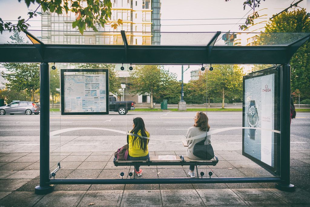 Dwie kobiety czekające na przystanku autobusowym.